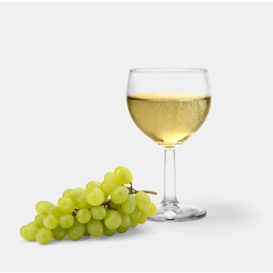 Glass of chilled white wine placed beside a bunch of fresh green grapes on a light background.