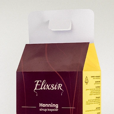 Top view of the Elixsir Honey syrup capsules box, showing the open white flap and brown-and-yellow packaging design with the Elixsir logo and flavor name.