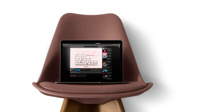 Laptop on a pink chair showing a YouTube video of a Daells Bolighus animation.