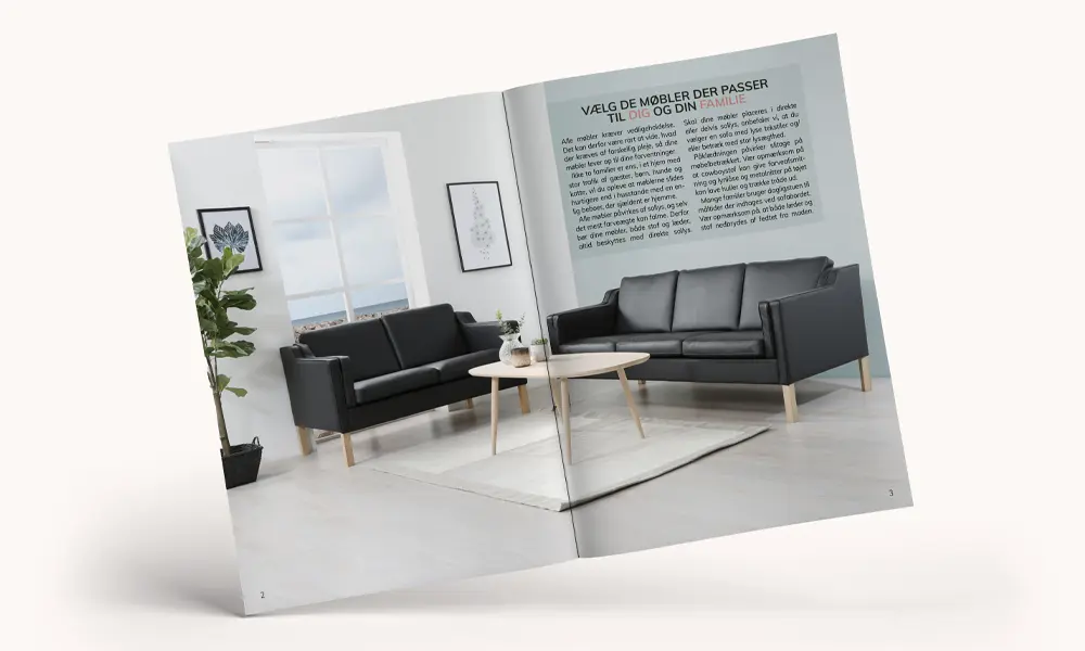 Furniture catalog opened to a spread showing two black leather sofas in a bright Scandinavian interior.