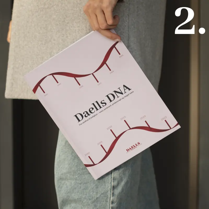Person holding the Daells DNA catalogue with a red timeline design on the cover, created as part of a design apprenticeship project.
