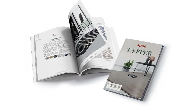 Two catalogs. One closed and one open, showcasing Daells Bolighus carpet designs and interior photos.