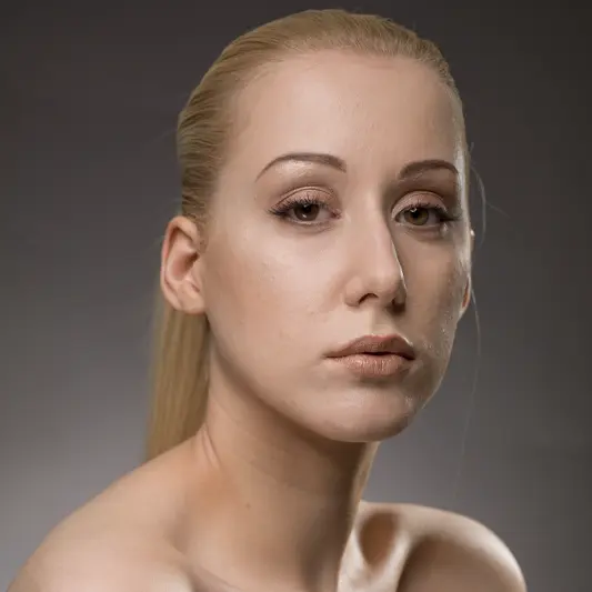 Unretouched version of the beauty portrait with blonde hair, neutral expression, and natural skin texture.